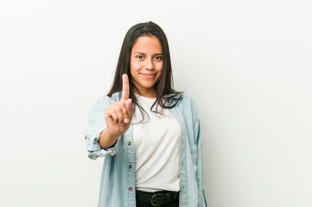 Jonge Spaanse vrouw die nummer één met vinger toont.