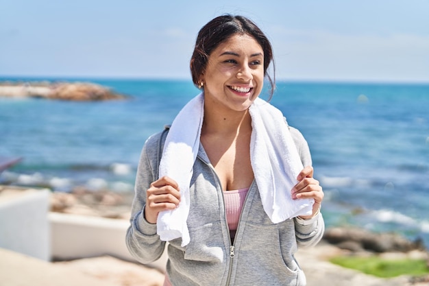 Jonge spaanse vrouw die sportkleding draagt die zich bij kust bevindt