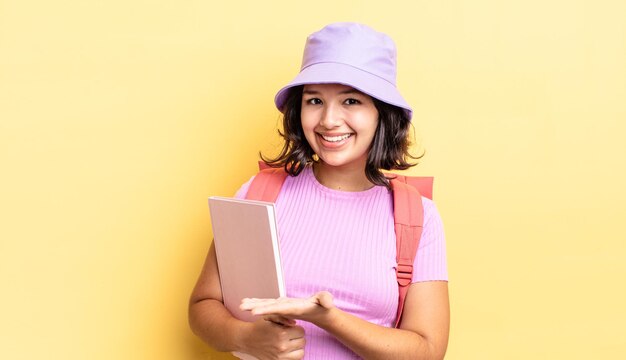 Jonge spaanse vrouw die vrolijk lacht, zich gelukkig voelt en een concept toont. terug naar school concept