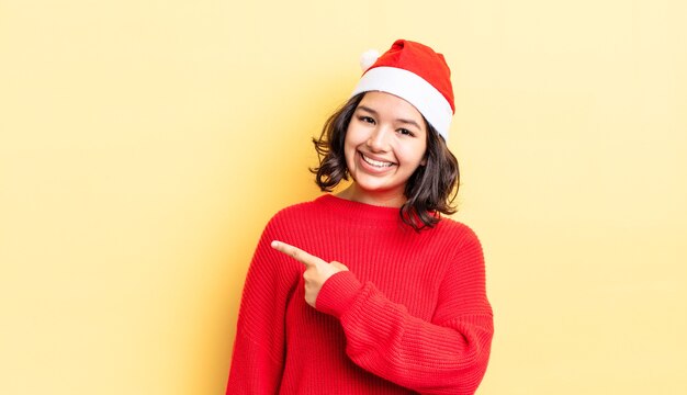 Jonge spaanse vrouw die vrolijk lacht, zich gelukkig voelt en naar de zijkant wijst. kerst concept