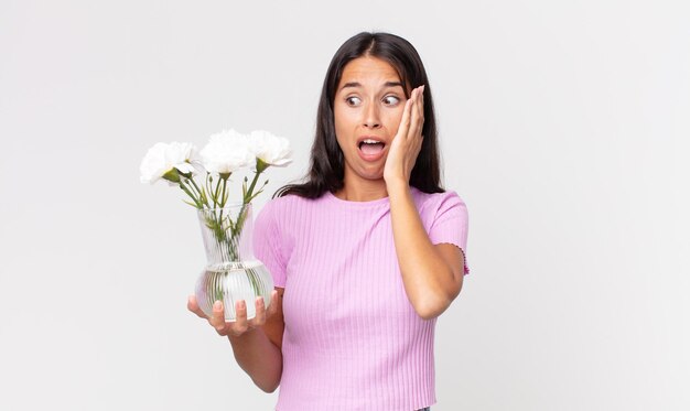 Jonge Spaanse vrouw die zich gelukkig, opgewonden en verrast voelt met decoratieve bloemen