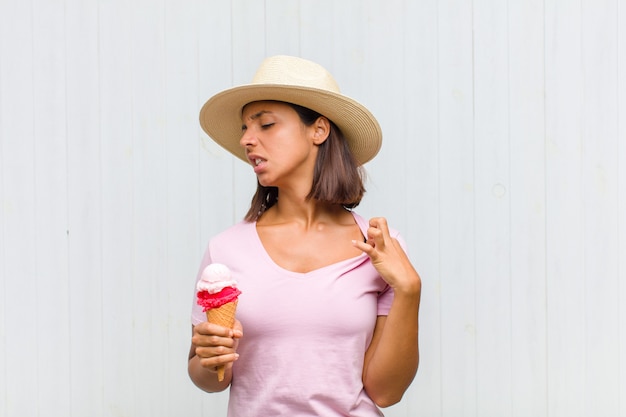 Jonge Spaanse vrouw die zich gestrest, angstig, moe en gefrustreerd voelt, aan de hals van het shirt trekt, gefrustreerd kijkt door het probleem