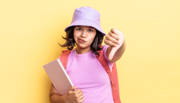 Jonge spaanse vrouw die zich kruis voelt en duimen naar beneden laat zien. terug naar school concept