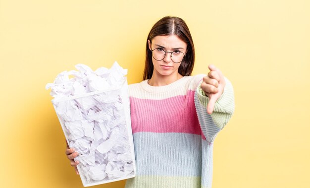 Jonge spaanse vrouw die zich kruist met duimen naar beneden mislukking prullenbak concept