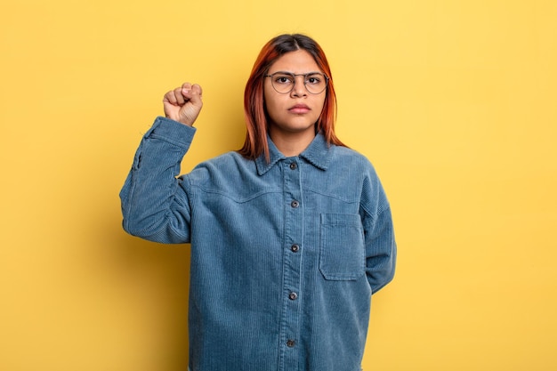 Jonge Spaanse vrouw die zich serieus, sterk en rebels voelt, vuist opheft, protesteert of vecht voor revolutie