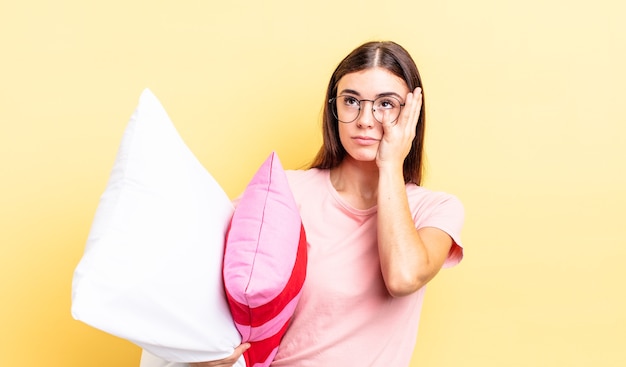 Jonge spaanse vrouw die zich verveeld, gefrustreerd en slaperig voelt na een vermoeiende pyjama en kussenconcept