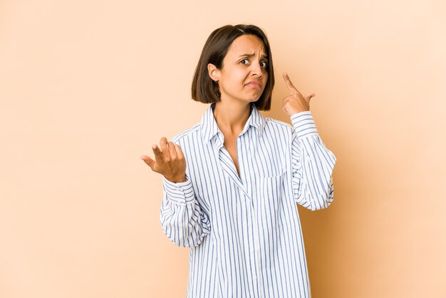 Jonge Spaanse vrouw geïsoleerd bedrijf en een product bij de hand tonen.