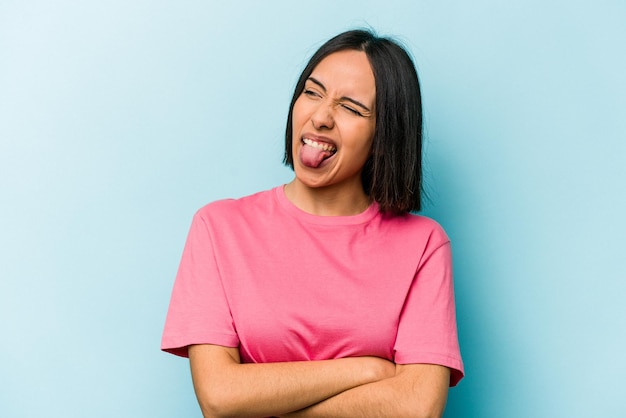 Jonge Spaanse vrouw geïsoleerd op blauwe achtergrond grappig en vriendelijk tong uitsteekt