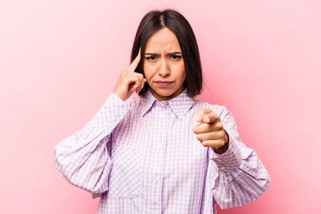 Jonge Spaanse vrouw geïsoleerd op roze achtergrond wijzende tempel met vinger denken gericht op een taak