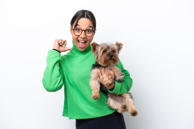 Jonge Spaanse vrouw met een hond geïsoleerd op een witte achtergrond trots en zelfvoldaan