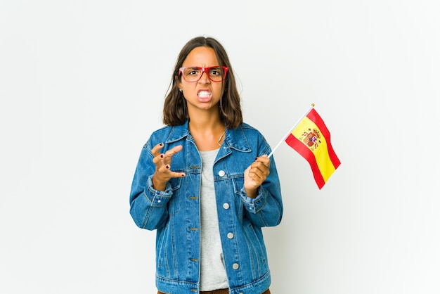 Jonge Spaanse vrouw met een vlag geïsoleerd boos schreeuwen met gespannen handen.