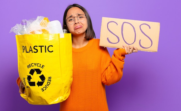 Jonge spaanse vrouw. recycle concept, plakkaat met tekst sos te houden