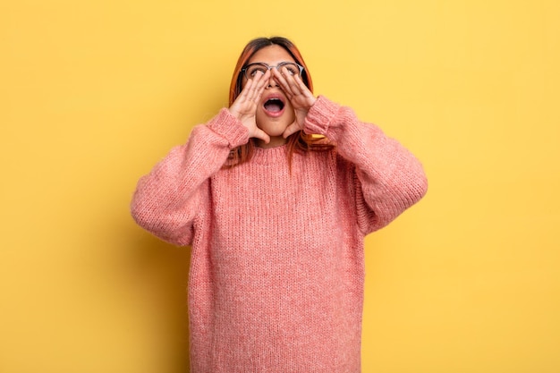 Jonge Spaanse vrouw voelt zich gelukkig opgewonden en positief en geeft een grote schreeuw met de handen naast de mond die roept