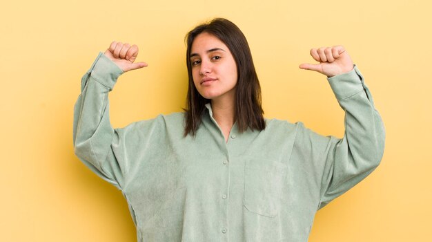 Jonge Spaanse vrouw voelt zich trots, arrogant en zelfverzekerd en ziet er tevreden en succesvol uit terwijl ze naar zichzelf wijst