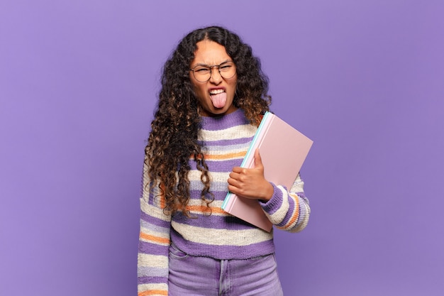 Jonge Spaanse vrouw walgt en geïrriteerd, steekt tong uit, houdt niet van iets smerigs en vies. student concept