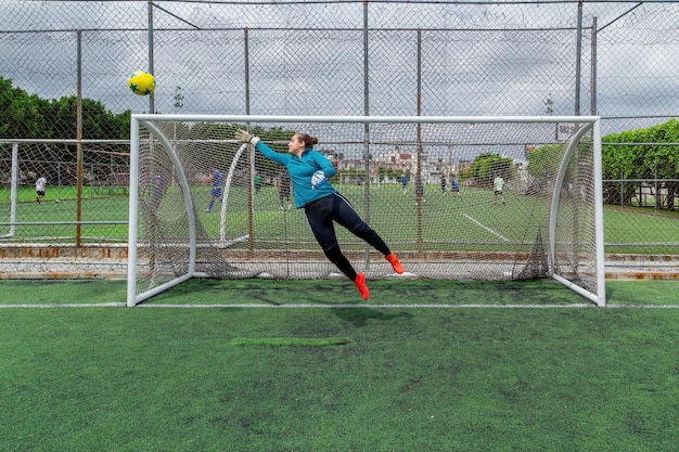 Jonge Spaanse vrouwelijke keeper die een bal probeert te vangen
