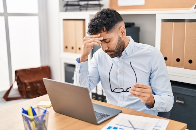 Jonge Spaanse zakenman benadrukte het gebruik van een laptop die op kantoor werkte