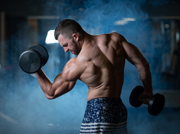 Jonge spiermens die met domoren uitoefent. Guy traint zijn biceps