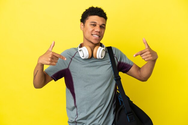 Jonge sport Afro-Amerikaanse man met sporttas geïsoleerd op gele achtergrond trots en zelfvoldaan