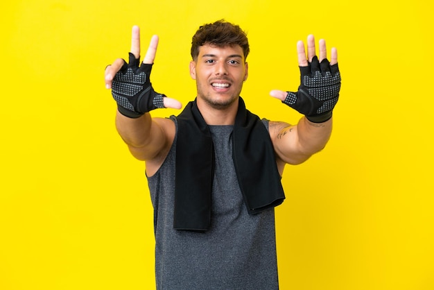 Jonge sport blanke man met handdoek geïsoleerd op gele achtergrond acht tellen met vingers
