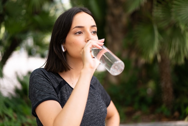 Jonge sport blanke vrouw met een fles water in de buitenlucht in een park