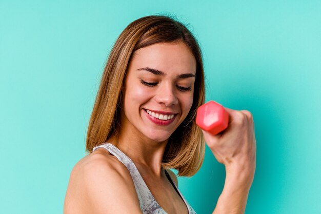 Jonge sport magere Kaukasisch die een domoorvrouw houden die op blauwe muur wordt geïsoleerd