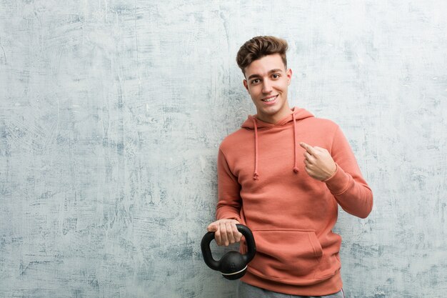 Foto jonge sport man met een halter verrast wijzend op zichzelf, breed glimlachend.