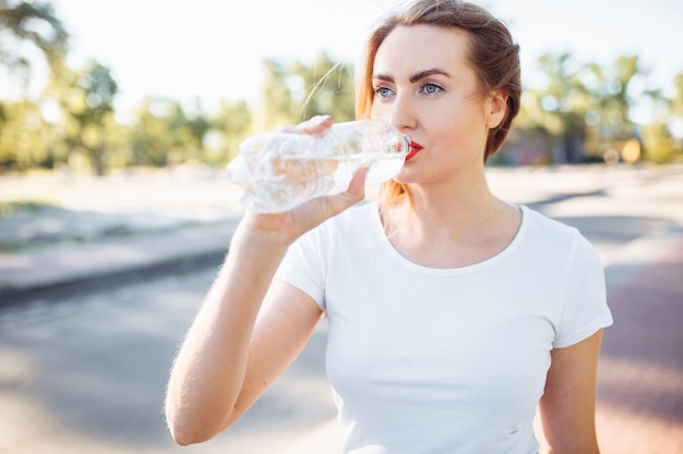 Jonge sport meisje, drinkwater uit de fles, na een zware training.