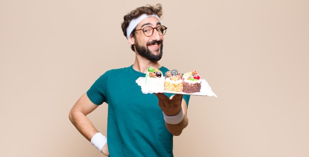 Jonge sportenmens met cakes op vlakke muur