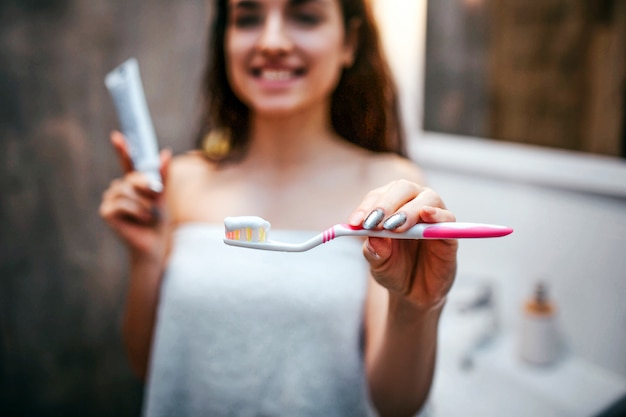 Foto jonge sportieve donkerharige mooie vrouw die de routine van de ochtendavond bij spiegel doet.