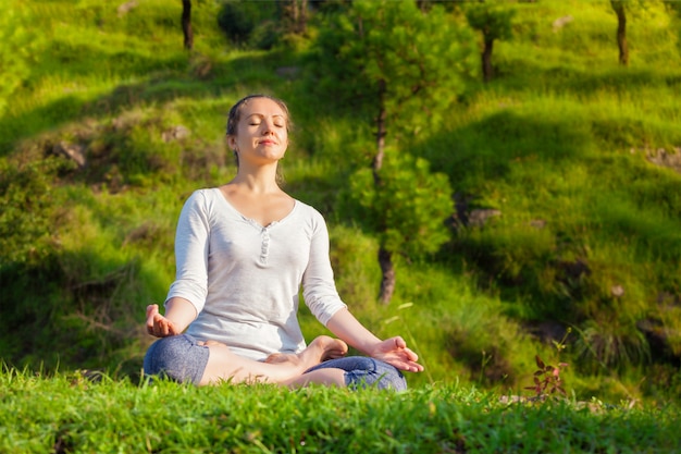 Jonge sportieve fit vrouw in yoga Lotus pose oudoors