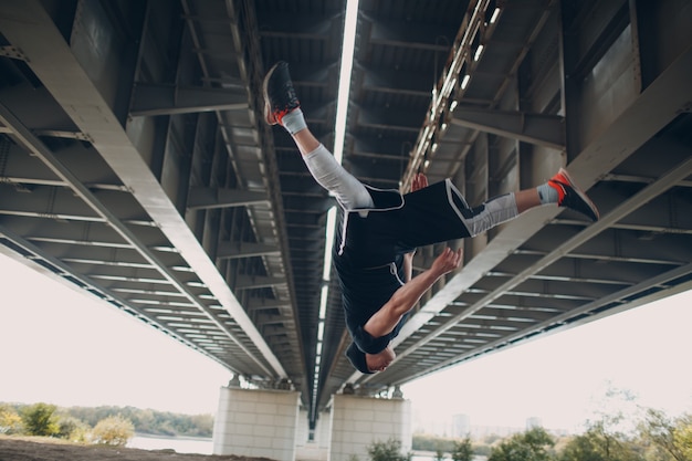 Foto jonge sportieve kerel die parkour doet bij de stadsstraat.