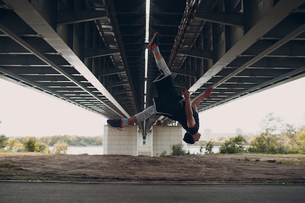 Jonge sportieve kerel die parkour doet bij de stadsstraat.