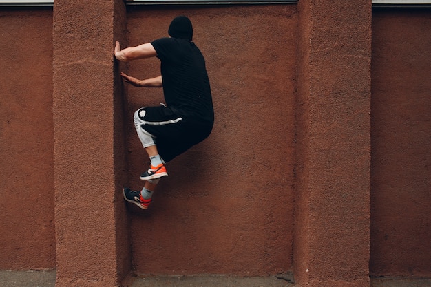 Jonge sportieve kerel die parkour doet bij de stadsstraat.