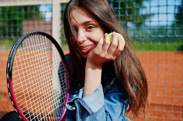 Jonge sportieve meisjesspeler met tennisracket op tennisbaan.