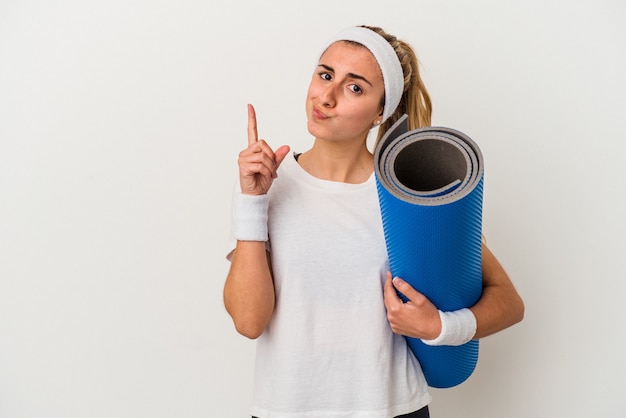 Jonge sportieve vrouw die een mat houdt die nummer één met vinger toont.