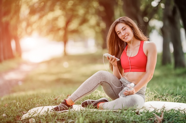 Jonge sportieve vrouw die in het park na opleiding rust