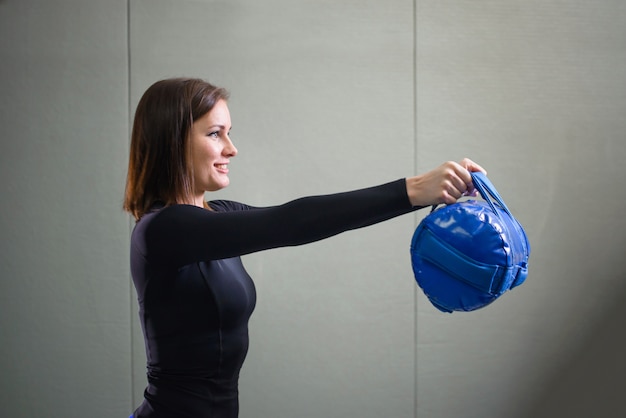 Jonge sportieve vrouw die met geschiktheidstas bij gymnastiek uitwerken