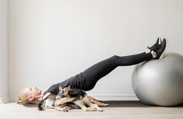 Jonge sportieve vrouw die op de fitnessbal zit en zich opwarmt voor de training