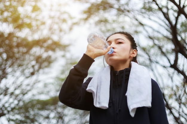 jonge, sportieve vrouw drinkwater in het park