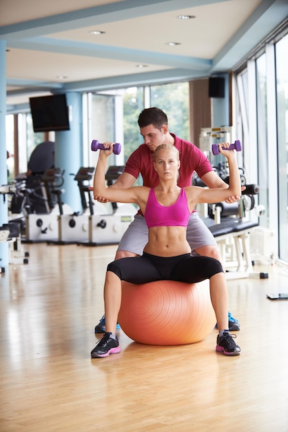 jonge sportieve vrouw met trainer oefenen gewichten opheffen in fitness gym