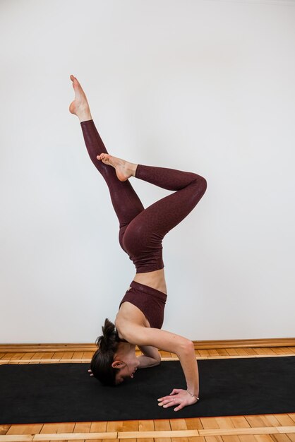 Jonge sportieve vrouwelijke trainer die yoga beoefent in de studio stretching oefening