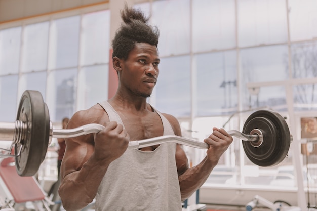 Jonge sportman die met barbell uitwerkt