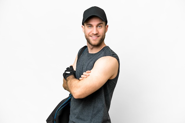 Jonge sportman met sporttas over geïsoleerde witte achtergrond met gekruiste armen en vooruit kijkend