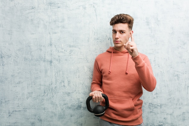 Jonge sportmens die een domoor houden die nummer één met vinger tonen.