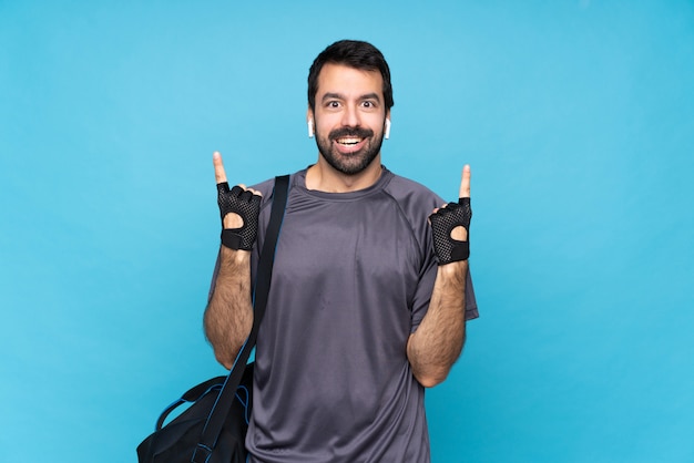 Jonge sportmens die met baard over geïsoleerd blauw een groot idee benadrukken