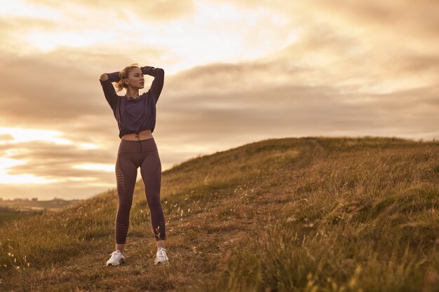 Jonge sportvrouw aan het opwarmen in de natuur