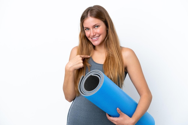 Jonge sportvrouw die naar yoga gaat terwijl ze een mat vasthoudt met een verrassende gezichtsuitdrukking