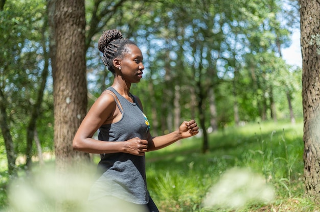 Jonge sportvrouw die op een zonnige dag in het bos loopt