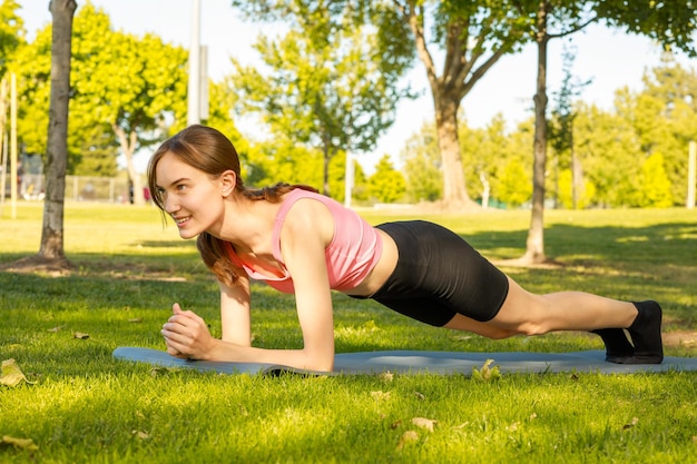 Jonge sportvrouw die plank doet in het park